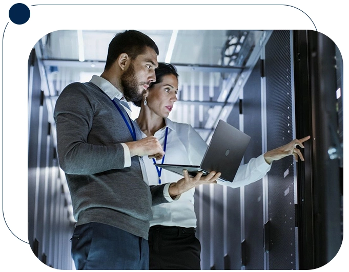 Two people in a room with one holding a laptop